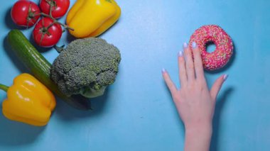 Kadın eli, abur cubur mu yoksa sağlıklı yiyecek mi seçeceğine karar veremiyor.
