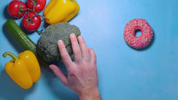 Um homem escolhe entre comida saudável e donut junk food — Vídeo de Stock