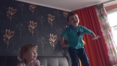 Çift kişilik yatakta zıplayan iki kardeş.