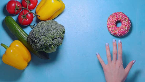 Female woman hand blue nails want to take donut but choose fresh yellow pepper — Stock Video