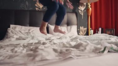 Neşeli çocuk yatakta hoplayıp zıplıyor