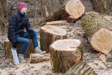 Zor çalışmalarından: genç kadın ormanda kocaman bir ağaç testereleri ve onun elinde bir testere ile dinlenme oturur