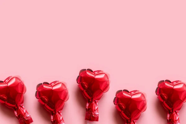 Borde de los globos de papel de aluminio rojo corazones sobre fondo rosa — Foto de Stock