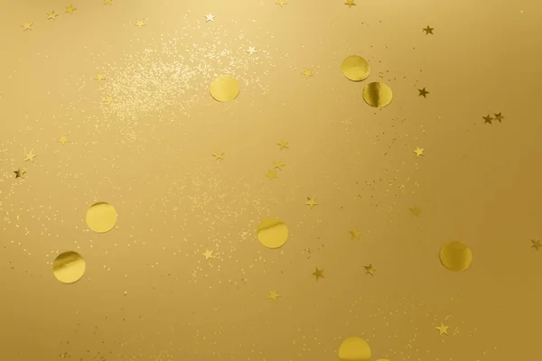 Gold confetti and glitter on beige metallic shiny background — ストック写真