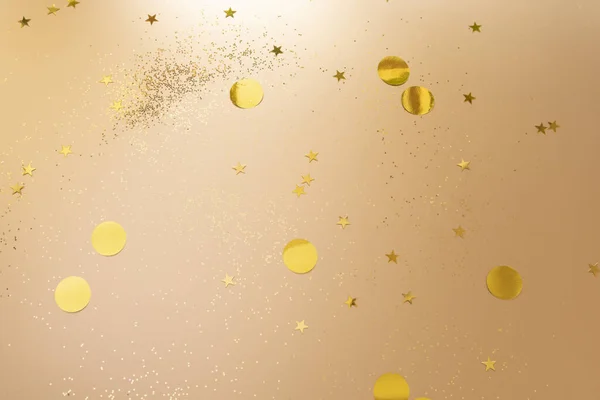 Gold confetti and glitter on beige metallic shiny background — ストック写真