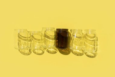 Sarı zemin üzerinde gölgeler olan boş cam şişeler.