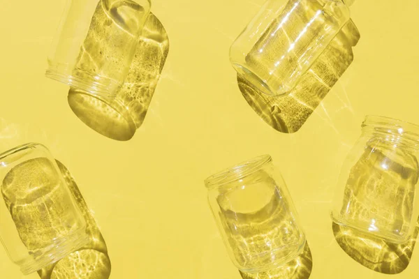 Botellas de vidrio vacías con patrón de sombras sobre fondo amarillo — Foto de Stock