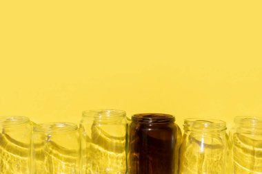 Sarı zemin üzerinde gölgeler olan boş cam şişeler.