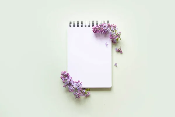Notebook met lila bloem op een mint groene achtergrond — Stockfoto