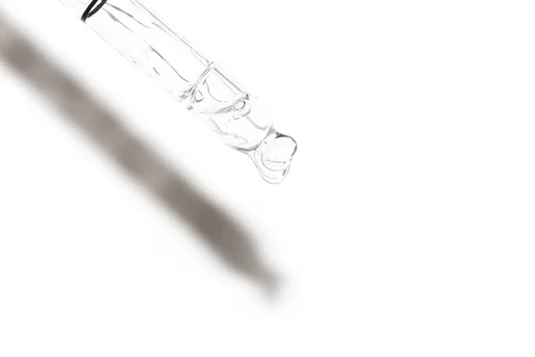 Макрос пипетки с жидкостью и капли на белом фоне — стоковое фото