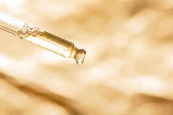 Sıvı ile pipette makro ve altın arkaplan üzerine damla