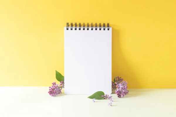 Notebook met lila bloemen op een geel groene achtergrond — Stockfoto