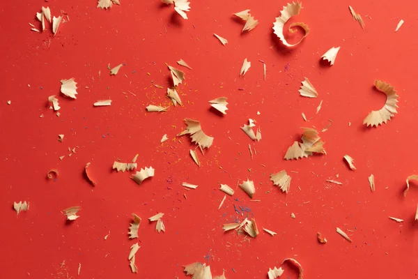 Lápis de cor raspas e lápis em um fundo vermelho — Fotografia de Stock