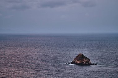 Gün batımında okyanus ve bulutlar Küçük bir adayla güneş ışınlarıyla