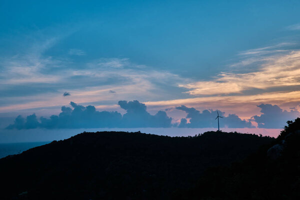 Wind turbine on top of a hill during sunset