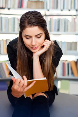 Öğrenci kız kitaplığındaki bir kitap, büyüledi okuma.