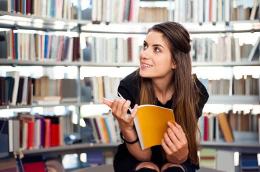 Öğrenci kıza bir kitaplığındaki bir kitap.