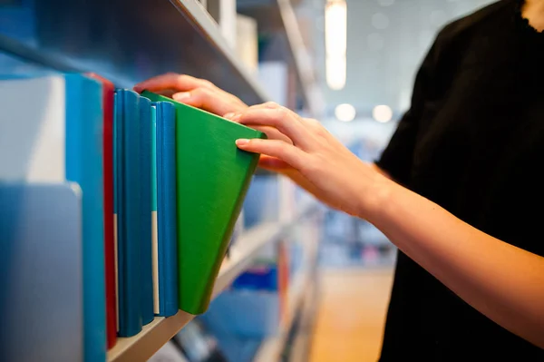 Mujer tomando un libro de la estantería — Foto de Stock