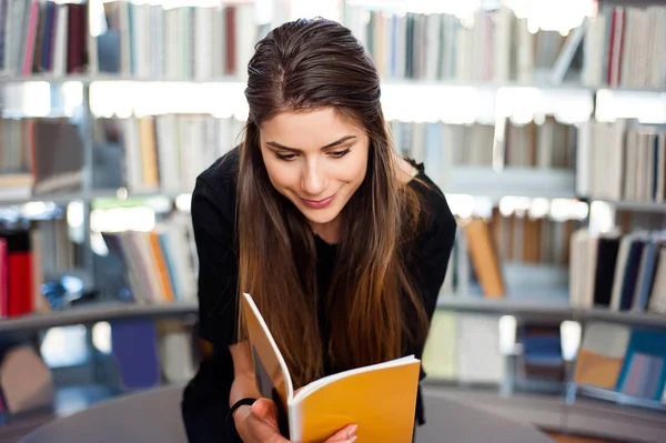 Dziewczyna Student w bibliotece, czytanie książki, zniewolony. — Zdjęcie stockowe