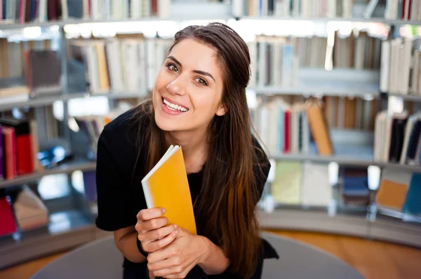 快乐的学生小女孩微笑着拿着一本书的图书馆 — 图库照片