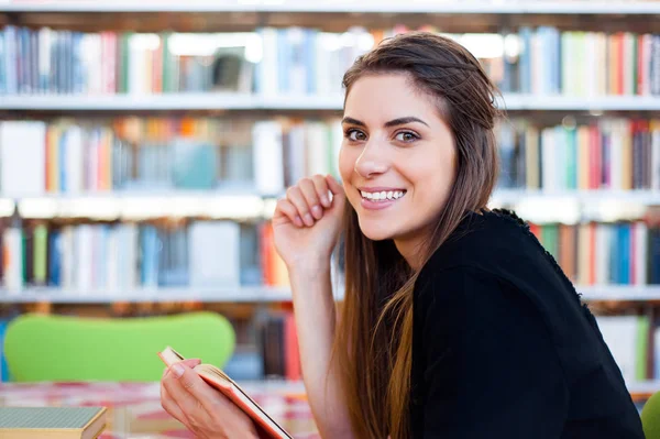 Studentin in einer Bibliothek sieht glücklich aus — Stockfoto