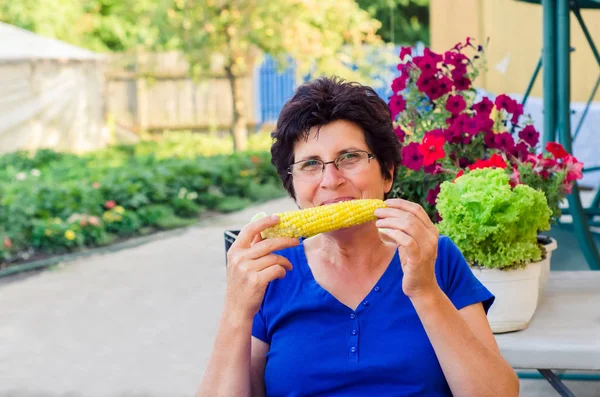 Γυναίκα τρώει βιο βρασμένο καλαμπόκι στο στάχυα από τον κήπο της — Φωτογραφία Αρχείου
