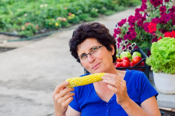 Vrouw bio eten gekookt suikermaïs op cobs uit haar tuin — Stockfoto