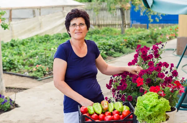 Старшая женщина со свежими овощами и цветами — стоковое фото