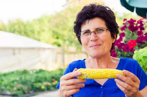 Жінка їсть біологічно зварену солодку кукурудзу на цицьки з її саду — стокове фото