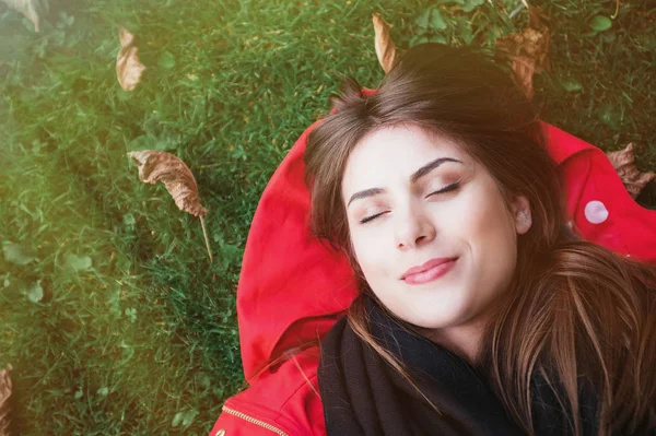 Vrouw zit in het groene gras met haar ogen gesloten. — Stockfoto