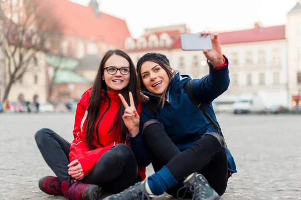 Ült az utcán, figyelembe véve a selfie lányok. — Stock Fotó