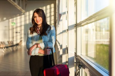 Arabası çanta ile Havaalanı terminal bekleme odasında genç kadın.