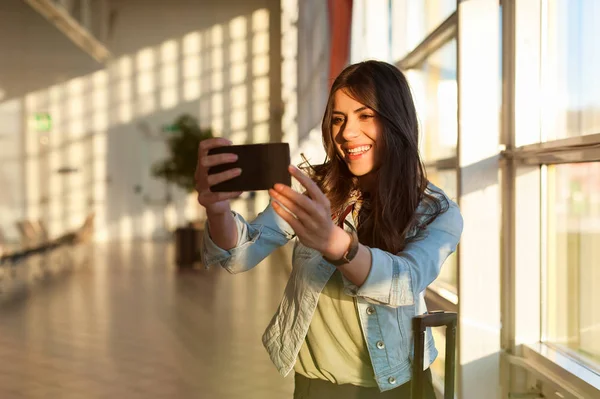 Frau macht am Flughafen ein Selbstporträt mit Handy — Stockfoto