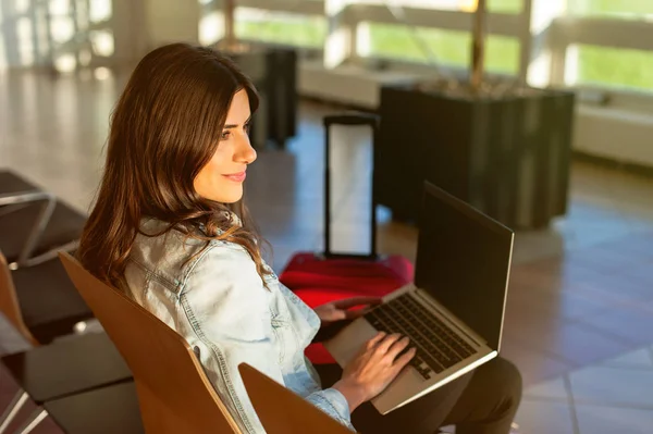 Flicka resor, sitter med laptop i flygplats väntrum — Stockfoto