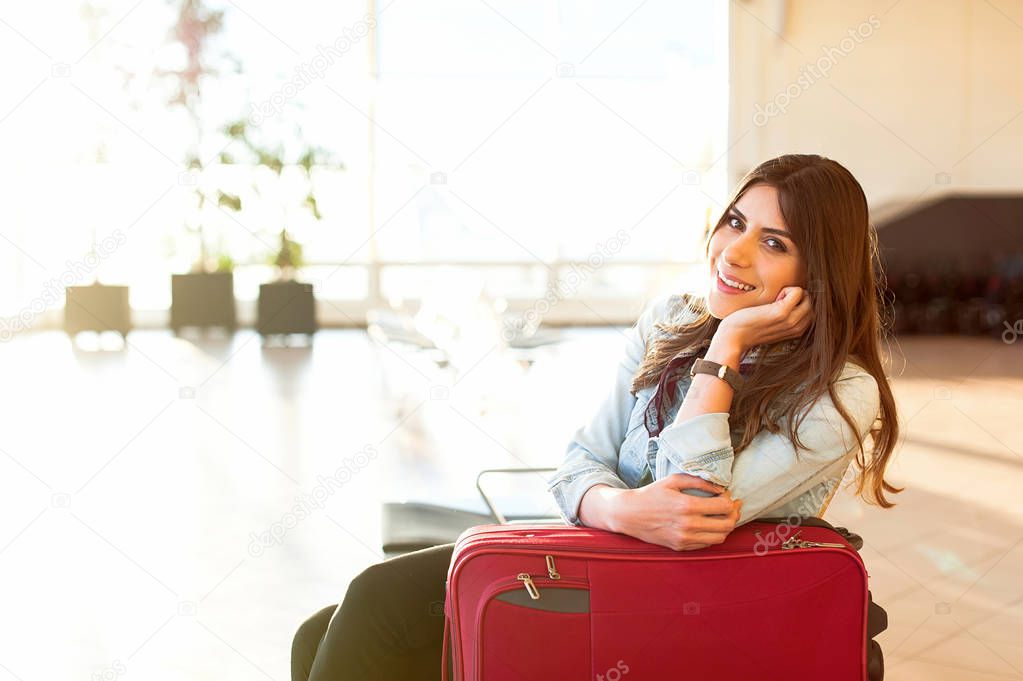 Young girl with trolly bag in airport waiting room.
