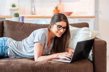 Modern teknolojiyi kullanarak kanepede oturan kadın