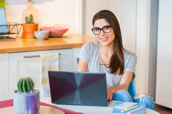 Chica sentada en casa trabajando / navegando en línea en su computadora portátil —  Fotos de Stock