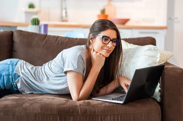 Femme assise sur le canapé en utilisant la technologie moderne — Photo