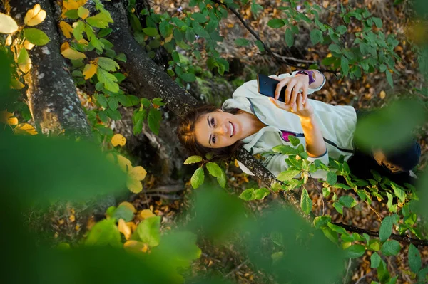 Donna salito in un albero a chiacchierare e sms su smart phone — Foto Stock