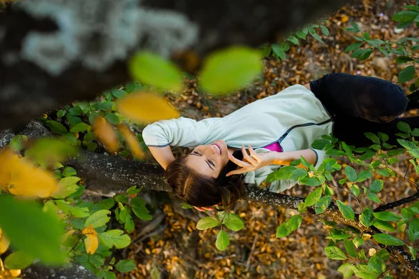 Akıllı telefonda konuşurken bir ağaçta oturan kadın