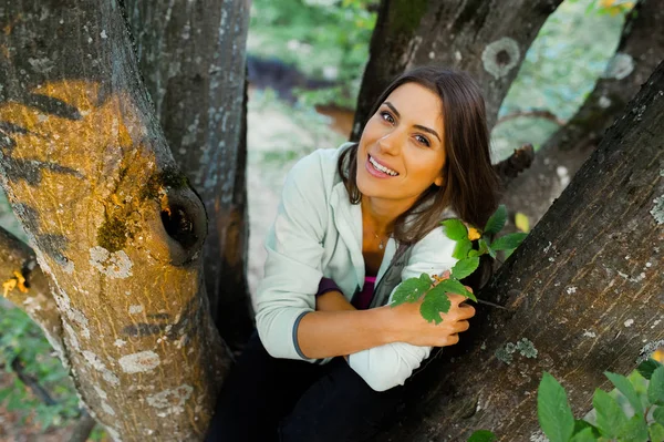 Genç kadın büyük ve eski bir ağaçta oturuyor