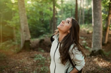 Genç kadın, ormanda bir yürüyüş sonra dinlenme sonbahar sezonunda günbatımı ışığı ormandaki bir sırt çantası taşıyan.