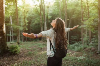 Genç kadın emgracing güneş ve doğa ile bakılması, elleri havada doğa keşfetmek gün batımı ışık Sonbahar sezonu, ormanın içinde sırt.
