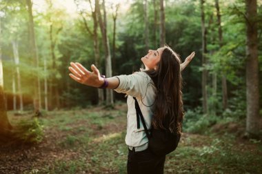 Genç kadın emgracing güneş ve doğa ile bakılması, elleri havada doğa keşfetmek gün batımı ışık Sonbahar sezonu, ormanın içinde sırt.