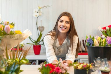 Smiling woman florist small business flower shop owner, at counter, looking friendly at camera. clipart