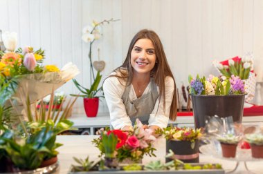 Smiling woman florist small business flower shop owner, at counter, looking frinedly at camera. clipart