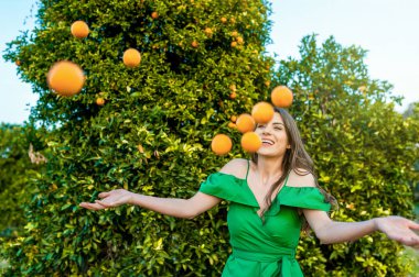 Neşeli genç kadın, açık havada oynarken, portakal Hava atma bir turuncu meyve bahçesi, günbatımında. Kavramı mutluluk ve sağlıklı yaşam konsepti, cilt ve saç bakımı.  