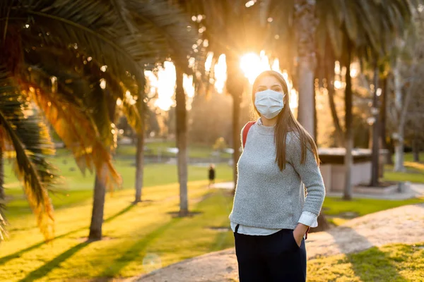 Young woman outdoor wearing face mask, social distancing isolated from other people wearing face protection.