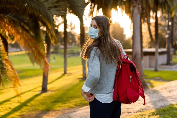 Young woman outdoor wearing face mask, social distancing isolated from other people wearing face protection.