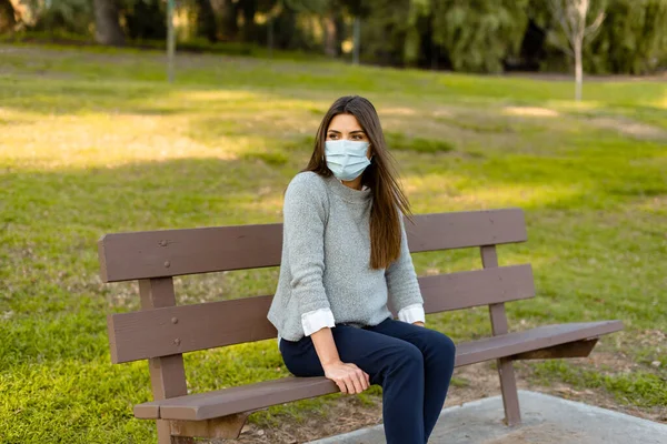 Ung Kvinna Utomhus Bär Medicinsk Ansiktsmask Social Distans Sitter Bänk Stockfoto